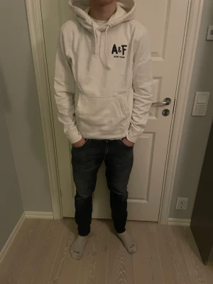Abercrombie & Fitch hoodie vit - Tja säljer en Snygg vit hoodie från Abercrombie & Fitch med svart A&F New York-tryck på bröstet. Klassisk känguruficka framtill, dragsko i huvan och mjukt material som känns skönt mot huden. Perfekt för en avslappnad och stilren archive/laidback look. Skicket är 9/10 ungefär helt ny🤗storlek L killen på bilden är 183 och ganska smal är lite för stor för han🤩har du några frågor eller funderingar är de bara att höra av sig🙌🏼mvh premium fashion😁