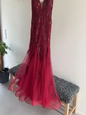 Vinröd långklänning från JJ's House - Elegant vinröd balklänning med v-ringning och öppen i rygg. Man kan justera hur löst/tight man vill att klänningen ska sitta med hjälp utav banden i ryggen. Klänningen har egentligen ett släp där bak, men jag lämnade in den hos sömmerskan för att ta bort det för ville inte att någon skulle trampa på den🥰 Nypris på klänningen är 2438kr, men pågrund av både frakten samt att ta bort släpet så kostade det mig ytterligare 2500kr så säljer jag den för lite mer än 2438kr, kontakta mig vid frågor!