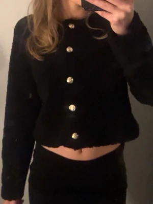 Svart kofta från H&M med guldknappar - Säljer en svart, fluffig kofta från H&M i storlek S. Funkar bra för nån som har xxs eller xs också!