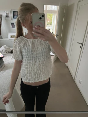 Vit croppad blus med smock - Säljer en vit croppad blus med smock och korta ärmar. Blusen har en rund halsringning och är tillverkad i ett lätt material som ger en luftig känsla. Perfekt för dig som gillar en enkel och stilren look.