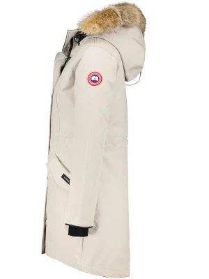 Ljusbeige parkas från Canada Goose - Snygg ljusbeige parkas från Canada Goose med avtagbar huva och pälsdetalj. Jackan har en klassisk logotyp på ärmen, långa ärmar med svarta muddar och praktiska fickor framtill. Perfekt för kalla dagar och riktigt varm.