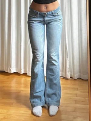 Ljusblå bootcut jeans från Levi's - Säljer ett par ljusblå bootcut jeans från Levi's med klassisk femficksdesign och hög midja. Jeansen har en snygg utsvängd passform och är tillverkade i denim. Perfekta för dig som gillar retrostil och vill ha ett par bekväma och trendiga jeans. Midjemått 39cm.