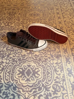 Addidas skor - Säljer ett par sjukt feta skor från addidas i brunt och röd sula. De sitter på mycket fint och funkar till typ allt, det finns tecken på användning men ändå fint skick. Även har tyget på sulan i ena skon lossnat men gör ingen skillnad. Hör av er vid minsta fundering!