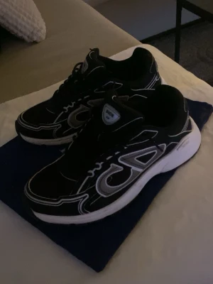 Svarta Dior B30 - Säljer ett par svarta Dior B30 med vit sula och vita detaljer. Skorna kom med vita snören men har valt själv att byta ut till svarta snören. Funkar lika bra att byta tillbaka till vita snören. Skorna har bra skick och CD logo med reflex material. Öppen för prisförslag!