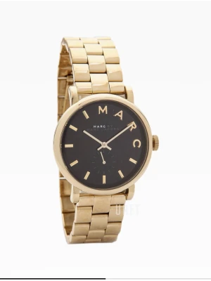 Guldig klocka från Marc Jacobs - Stilren klocka från Marc Jacobs med guldig länk och svart urtavla. Urtavlan har tydliga guldiga markeringar och bokstäverna M-A-R-C. Perfekt accessoar för att lyfta din outfit. Klockan ser helt ny ut och har inga skador på sig! Jag köpte klockan för 2500kr och säljer den för 1900kr! Pris går att diskutera!