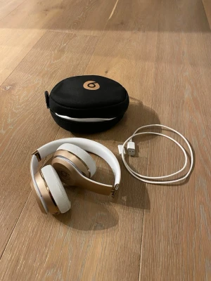 Beats Studio3 trådlösa hörlurar guld/vit - Snygga Beats Studio3 trådlösa over-ear hörlurar i vitt och guld. Kommer med matchande svart fodral och laddningskabel. Hörlurarna har mjuka öronkuddar och justerbar bygel för skön passform. Perfekta för musik, gaming eller videos.FINNS KVITTO! 