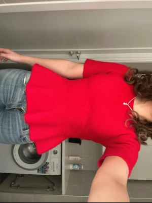 Röd ribbad topp med volang - Säljer en snygg röd topp med ribbad struktur och volang nedtill. Toppen har korta ärmar och en figurnära passform som framhäver midjan. Perfekt för dig som vill ha en färgstark och trendig look.