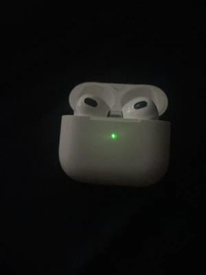 Apple AirPods med laddningsetui - Säljer ett par vita Apple AirPods med tillhörande laddningsetui. Trådlösa hörlurar med stilren och kompakt design, perfekt för musik, samtal och poddar. Laddningsetuiet har en LED-indikator på framsidan. Grymt smidiga att ta med överallt.