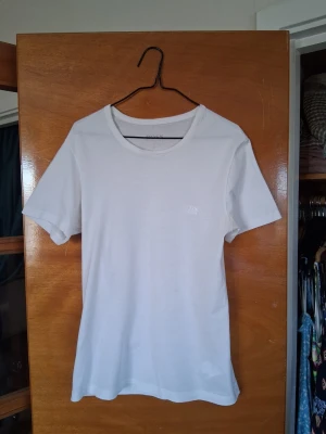 Vit t-shirt från BOSS - Snygg vit t-shirt från BOSS med diskret logga på bröstet. Klassisk rund halsringning och korta ärmar. Perfekt för en clean och stilren look! 😃 Några mindre, knappt synliga fläckar som går att tvätta bort.