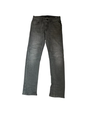 Grå jeans från Replay - Snygga grå jeans från Replay med klassisk femficksmodell och raka ben. Jeansen har en diskret tvättad look och är tillverkade i mjukt denimtyg som ger en skön passform. Perfekta för dig som gillar en stilren och avslappnad vibe.
