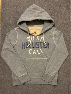 Vintage Hollister Hoodie - Extremt sällsynt och unik Hollister Hoodie med tryck | Hoodien har en unik sliten & distressed design! | Mycket bra skick, (lite smutsig vid högrs ärmen men syns knappast alls, se sista bild)| Storlek S | Längd≈ 65 cm, Bredd 55 cm under armhål-armhåla| Modell 175cm, 68kg | Priset ej hugget i sten! 