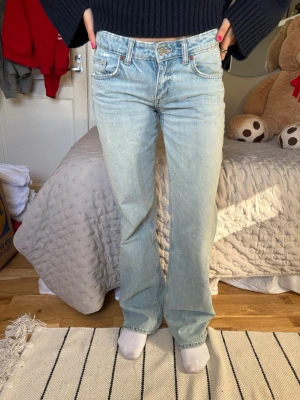 Ljusblå bootcut jeans  - Säljer ett par ljusblå bootcut jeans från Zara med klassisk femficksdesign och normal midja. Jeansen har en avslappnad passform genom benet och är tillverkade i denim. Perfekta för en casual och trendig look.