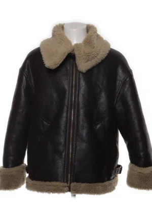 Shearlingjacka från Zara - En oversized svart skinnjacka med fluffigt beige foder och krage. Jackan har dragkedja framtill, två sidofickor och breda muddar i teddy-material. Perfekt för att hålla sig varm och samtidigt se cool ut. Materialet är syntetiskt och jackan har en klassisk aviatorstil.