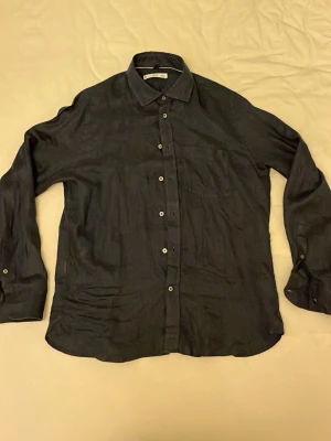 Mörkblå linneskjorta från Mango  - Säljer denna linneskjorta från Mango i storlek xs, passar även s. Det är dåligt ljus i bilderna men den är mörkblå. Plagget har en bröstficka. Passar för varmare dagar. I princip oanvänd, skriv vid frågor !