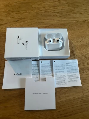 Apple AirPods 3  - Säljer ett par vita Apple AirPods 3 med trådlöst laddningsetui. Hörlurarna har in-ear-design och levereras i originalförpackning med tillhörande manualer. Helt nya 1:1