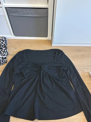 Svart och vit långärmad topp med twist - Två långärmade toppar i svart och vitt med twistad detalj framtill och lätt v-ringad hals. Tillverkade i mjukt bomullsmaterial och har en avslappnad passform. Perfekta för att lyfta din vardagsstil med en enkel men snygg look.