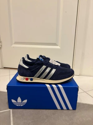 Adidas LA Trainer OG mörkblå - Tjena! Säljer dessa LA trainers i storlek 42 2/3. Dom är sprillans nya. Taggen är på. Det kommer med originalbox och vita skosnören. Skorna är bara provade en gång. Säljer skorna då de var lite för små.  Hör av er vid frågor!