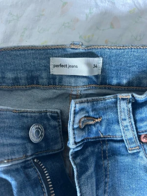 Blå raka jeans från Perfect Jeans - Säljer ett par klassiska blå jeans från Perfect Jeans i storlek 34. Jeansen har rak passform, normal midja och snygga detaljer vid fickor och knapp. Perfekta till vardagslooken och passar till det mesta. Materialet är mjukt denim som sitter bekvämt hela dagen. Passar storlek 36 med