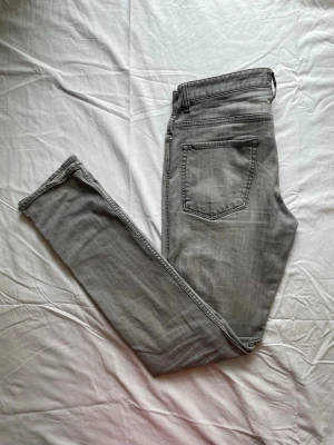 Hugo Boss jeans gråa  - Snygga grå slim fit jeans med klassisk femficksdesign och normal midja. Jeansen har en tvättad look och raka ben. Perfekta till en avslappnad streetstyle eller att matcha med en hoodie.