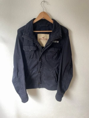 Mörkblå jacka från Hollister - Mörkblå vår jacka från hollister. Den är för stor på modellen som man ser på bild 3. Modellen är 178cm och väger 70kg ungefär. Hör gärna av er vid intresse!