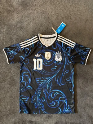 Argentina VM 26/27 borta Messi 10 - Fotbollströja med Messi på ryggen. Tröjan är helt ny med tagg kvar och i perfekt skick. Perfekt för dig som är supporter, samlar på fotbollströjor eller vill ha en snygg tröja till träning och vardag.                                                                      ▪️ Skickas inom 24 timmar.                                         Vid intresse eller frågor är det bara att skicka 👍
