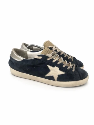 Golden Goose navy blue  - Snygga sneakers från Golden Goose i svart mocka med beige stjärndetalj på sidan och silvriga detaljer vid hälen. Skorna har beige snörning och en klassisk låg modell. Perfekta för dig som gillar en cool och avslappnad stil.
