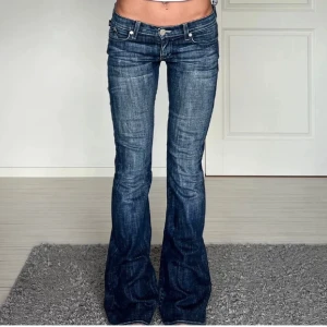 Rock & Republic bootcut jeans blå - Säljer ett par snygga blå bootcut jeans från Rock & Republic med vita broderade loggor på bakfickorna. 40 cm rakt över, innerben L  84 cm. Waist 27