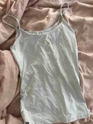 Vit linne - Säljer en enkel och stilren vit linnetopp från Zara. Toppen har smala axelband och ärmlös design, perfekt för varma dagar eller som lager under andra plagg. Materialet är mjukt och lätt, vilket gör den superbekväm att bära.