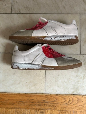 Masion margiela Japan gats 🔥🔥🙌 - Säljer dessa Masion margiela gats med grått tåparti och en stor röd cirkel på framsidan. Skorna har vita och röda skosnören och brun sula. Materialet är läder och mocka, och designen är retroinspirerad med låg profil. Hör av er vid det minsta 🔥🙌🙌