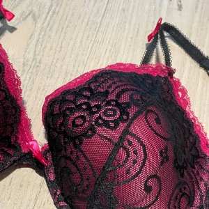 Svart och ceriserosa spets-bh - Säljer en snygg bh med svart spets och ceriserosa detaljer. Lappen är tyvärr avriven men skulle uppskatta storleken som en M, eller runt C kupa! 