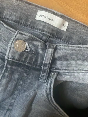Grå bootcut jeans  - Säljer ett par grå bootcut jeans från Perfect Jeans i storlek 32. Jeansen har en snygg tvättad look, klassisk femficksmodell och utsvängda ben. Perfekta till sneakers eller boots och tillverkade i mjukt denimtyg.