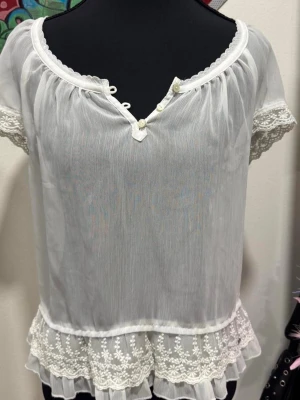 Romantisk blus från Ambercrombie & Fitch - 🤍 Romantisk topp från Abercrombie & Fitch i tunn chiffong med vackra spetsdetaljer och volangkant.  Lätt och luftig modell med feminina detaljer, dekorativa knappar framtill och spets på både ärmar och nederkant. 