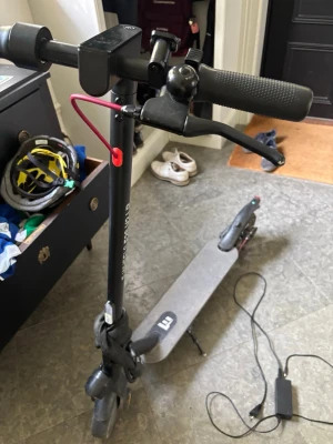 Svart elscooter med laddare - Säljer en svart elscooter med ringklocka och handbroms. Scootern har en bred ståplatta, gummihandtag och medföljer laddare. Perfekt för att ta sig runt i stan på ett smidigt sätt. Enkel att använda och ladda.