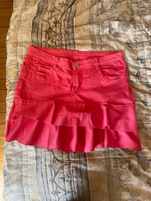 Jeansvolangkjol - Säljer den här unika egensydda jeanskjolen med spetsdetaljer på bakfickorna. Jeanskjolen är i en sån fin rosa färg och perfekt nu till sommaren. Midjemått 39 cm💗