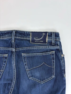 Mörkblå jeans från Jacob Cohën - Snygga mörkblå jeans från Jacob Cohën med raka ben och klassisk femficksdesign. Jeansen har kontrastsömmar och en patch med logga bak i midjan. Tillverkade i mjuk denim med en stilren look.