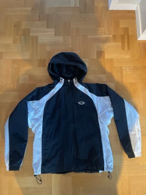 Corteiz Windbreaker Spring Jacket - En Corteiz Windbreaker Spring Jacket i väldigt bra skick. Det finns en mindre liten fläck på baksidan av högerärmen, knappt märkbar. Jackan har två sidofickor, och både luvan samt botten av jackan kan justeras i storlek. Storlek:M.