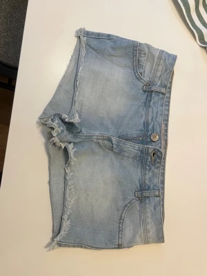 Lågmidjade Ljusblå jeansshorts - Säljer dessa väldigt lågmidjade jeansshorts pågrund av att dem tyvärr är försmå för mig. Perfekta för sommaren!!💞 Midjemåttet- 40cm tvärs över. Grenmåttet- 21,5❣️ 