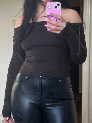 Brun offshoulder topp med långa ärmar - Trendig brun offshoulder topp med långa ärmar och tight passform. Perfekt att styla med höga byxor eller kjol för en snygg look. Mjuk och stretchig känsla.