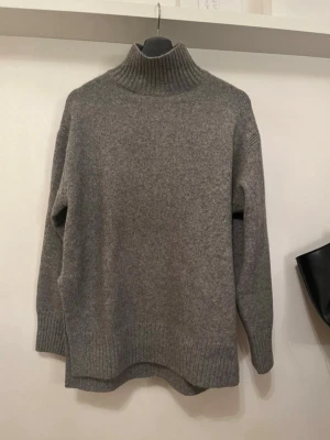 Grå polotröja i ullmix - Supersöt mysig grå stickad polotröja med hög krage och ribbade muddar från HM. Perfekt till sommaren tillsammans med en kjol!! 🥰