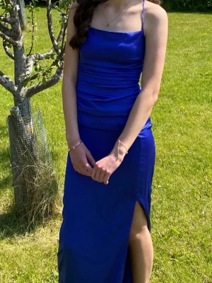 Blå långklänning med slits - Xs-S Elegant blå långklänning med smala axelband och figurnära passform. Klänningen har en snygg slits framtill och en stilren, enkel design som ger en modern look. Perfekt för speciella tillfällen under sommaren och avslutning eller bal. Skriv vid funderingar ❤️