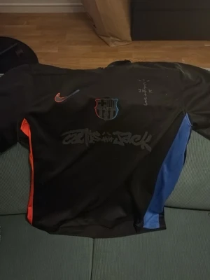 FC Barcelona matchtröja Nike svart - Säljer en svart FC Barcelona matchtröja från Nike med röda och blå detaljer på sidorna. Tröjan har klubbens emblem på bröstet, Nike-logga och tryck med F. De Jong 21 på ryggen. Materialet är lätt och andas, perfekt för fotboll eller träning.