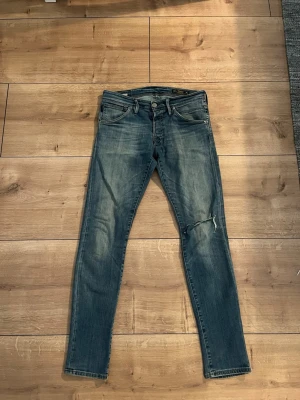 Jack & Jones jeans - Säljer dessa jeans från Jack & Jones i modellen slim fit Glenn. Jeans har ett hål i känt men det är själva slitningen. Storlek W32 L34. Själva pagen på baksidan är lite sliten men förutom de så är dom i fint skick. Hör av dig vid intresse eller minsta fråga.