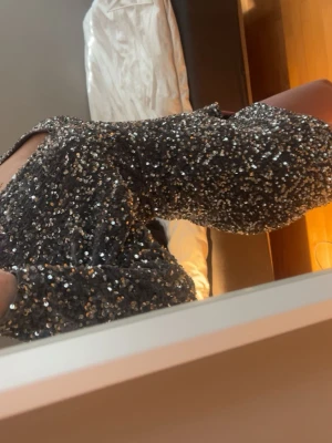 Glittrig paljettklänning från Forever 21 – strl M (passar S) ✨ - Superfin och glittrig paljettklänning från Forever 21. perfekt för fest, nyår eller utekväll ✨  Klänningen är helt täckt i silver/svarta paljetter som ger ett riktigt lyxigt och iögonfallande glow. Den har en figurnära passform med markerad midja och en elegant off shoulder/vid ringning som framhäver axlarna snyggt. Långa ärmar ger en balanserad och chic look. Storlek M men liten i storleken – passar även S (jag är själv S). Kort modell som sitter tight och smickrande på kroppen. Använd 1 gång