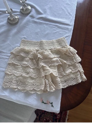 Beige spetsshorts med volanger - Superfina beige virkade shorts med flera lager volanger. De har en elastisk midja och är perfekta för varma dagar.