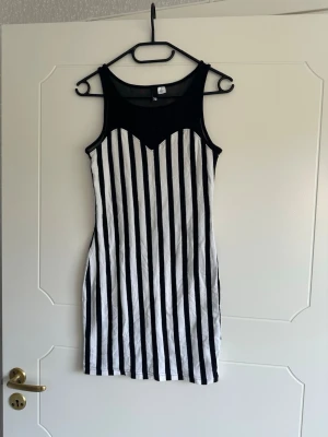 Klänning - Knälång klänning med mesh upptill. Finns en liten fläck men syns knappt. 