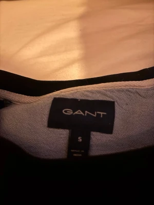 Svart sweatshirt från GANT - Svart sweatshirt från GANT med tryck 'GANT 1949' i vitt på bröstet. Klassisk rund halsringning och långa ärmar. Perfekt för en avslappnad och stilren look.