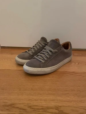 Grå mockasneakers, skolyx - Snygga grå sneakers i mocka med klassisk låg profil och vita sulor. Skorna är använda en sommar och mycket fina. De är från skolyx.