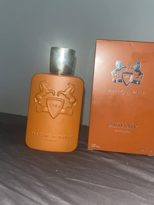 Parfums de Marly Althaïr parfym - Exklusiv parfym från Parfums de Marly, Althaïr. Flaskan är matt brun med silverfärgad kork och har ett elegant reliefmönster med två hästar och sköld. Kommer i matchande ask. Perfekt för dig som gillar lyxiga dofter och snygg design.