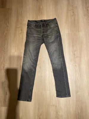 Grå slim fit jeans från Pull&Bear - Snygga grå slim fit jeans från jacl& Jones med klassisk femficksdesign och diskret tvättad look. Jeansen har normal midja, raka ben och är tillverkade i en mjuk bomullsblandning med lite stretch för extra komfort.