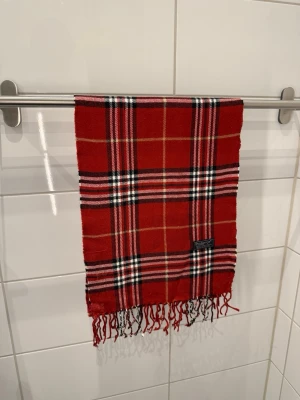 Burberrys Halsduk/Scarf Röd - Burberrys Halsduk / Scarf  Färg: Röd Material: 100% Lammull Unisex  Fint skick!